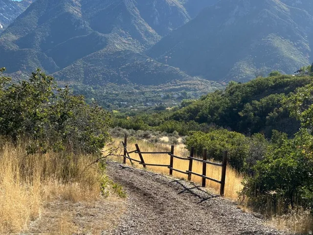 Mountain landscape with natural terrain, a gravel path, and wood fencing