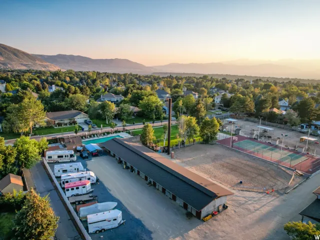 Expansive property featuring a large outdoor pool, multiple tennis courts, and a spacious gravel lot