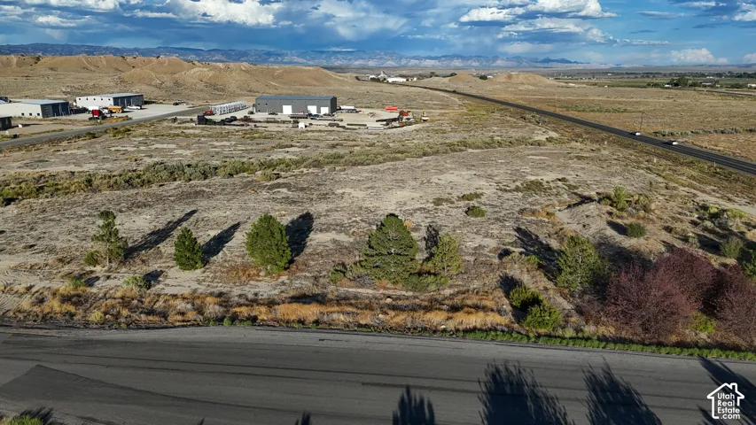 Expansive land parcel with direct road frontage, featuring natural vegetation and distant industrial structures