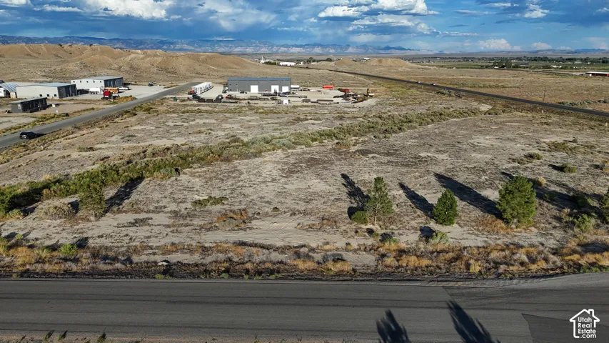 Expansive undeveloped land featuring natural desert vegetation, distant mountains, and established roads