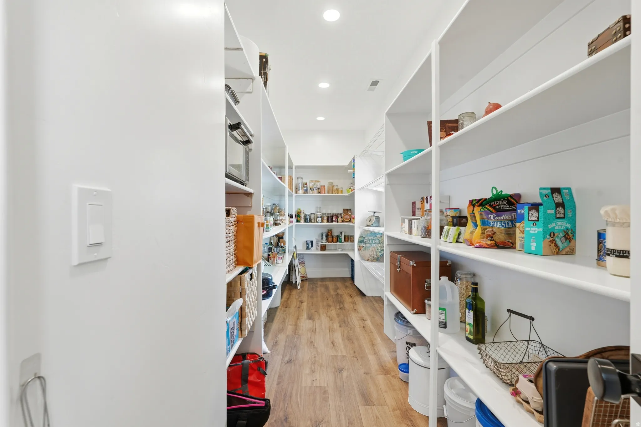 Expansive pantry featuring extensive shelving, recessed lighting, and wood-finish flooring
