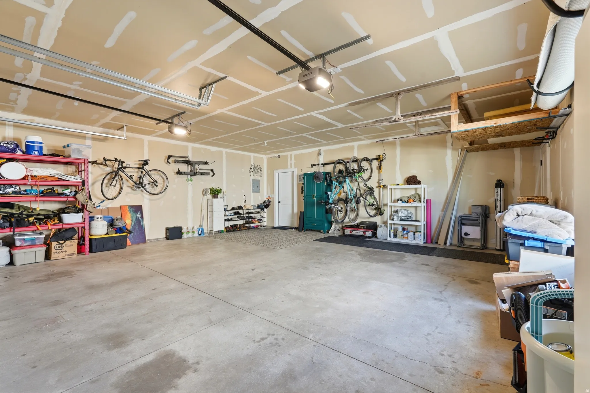 Attached garage featuring a concrete floor, painted drywall, overhead lighting, and an overhead storage platform