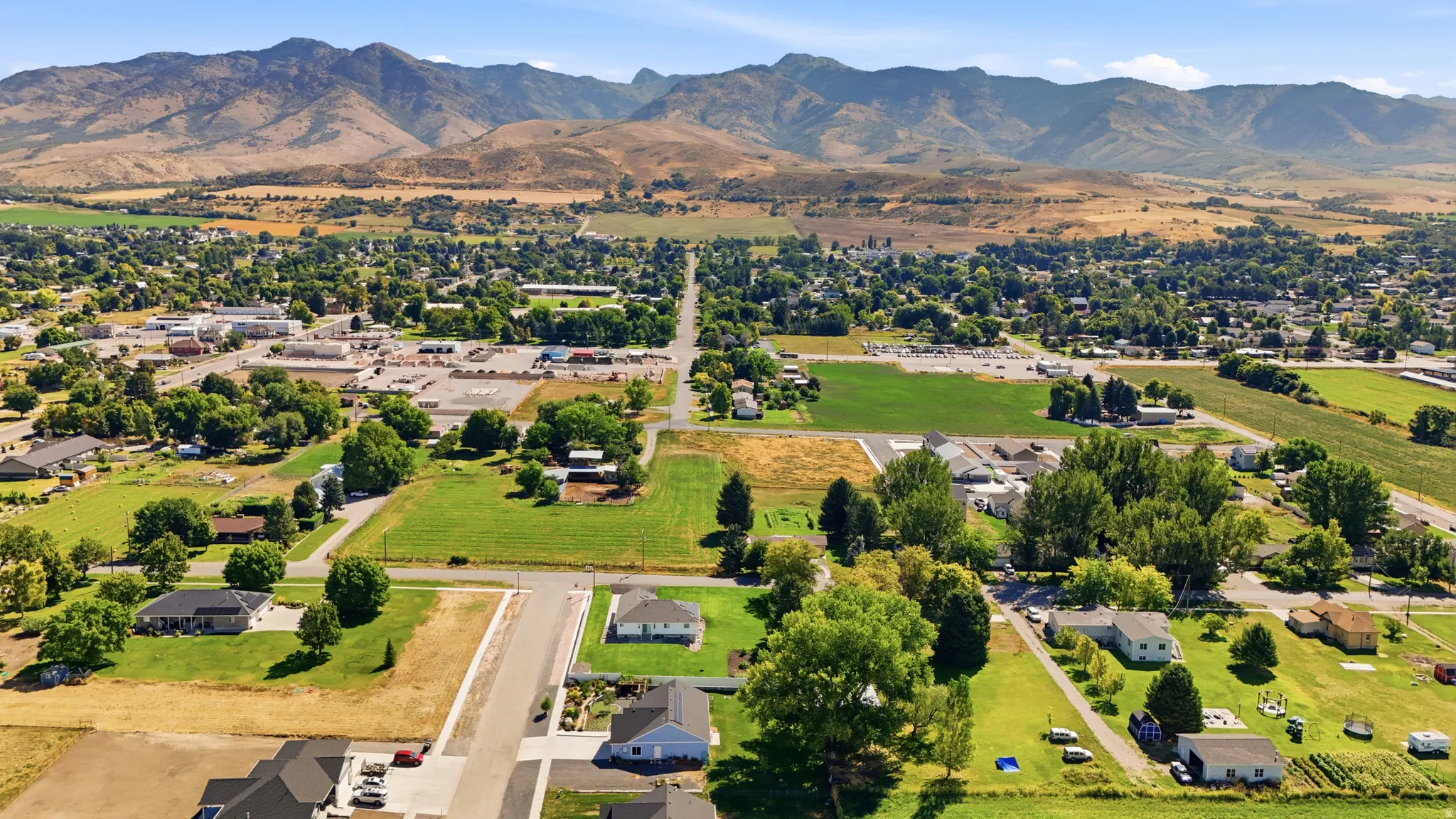 Expansive mountain backdrop with a visible community infrastructure including established residential areas, commercial buildings, and open green spaces