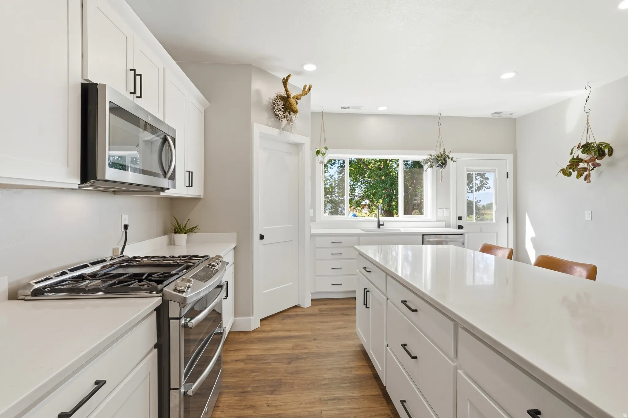 Kitchen featuring white cabinetry, stainless steel appliances, quartz countertops, a large center island, and wood-finish flooring