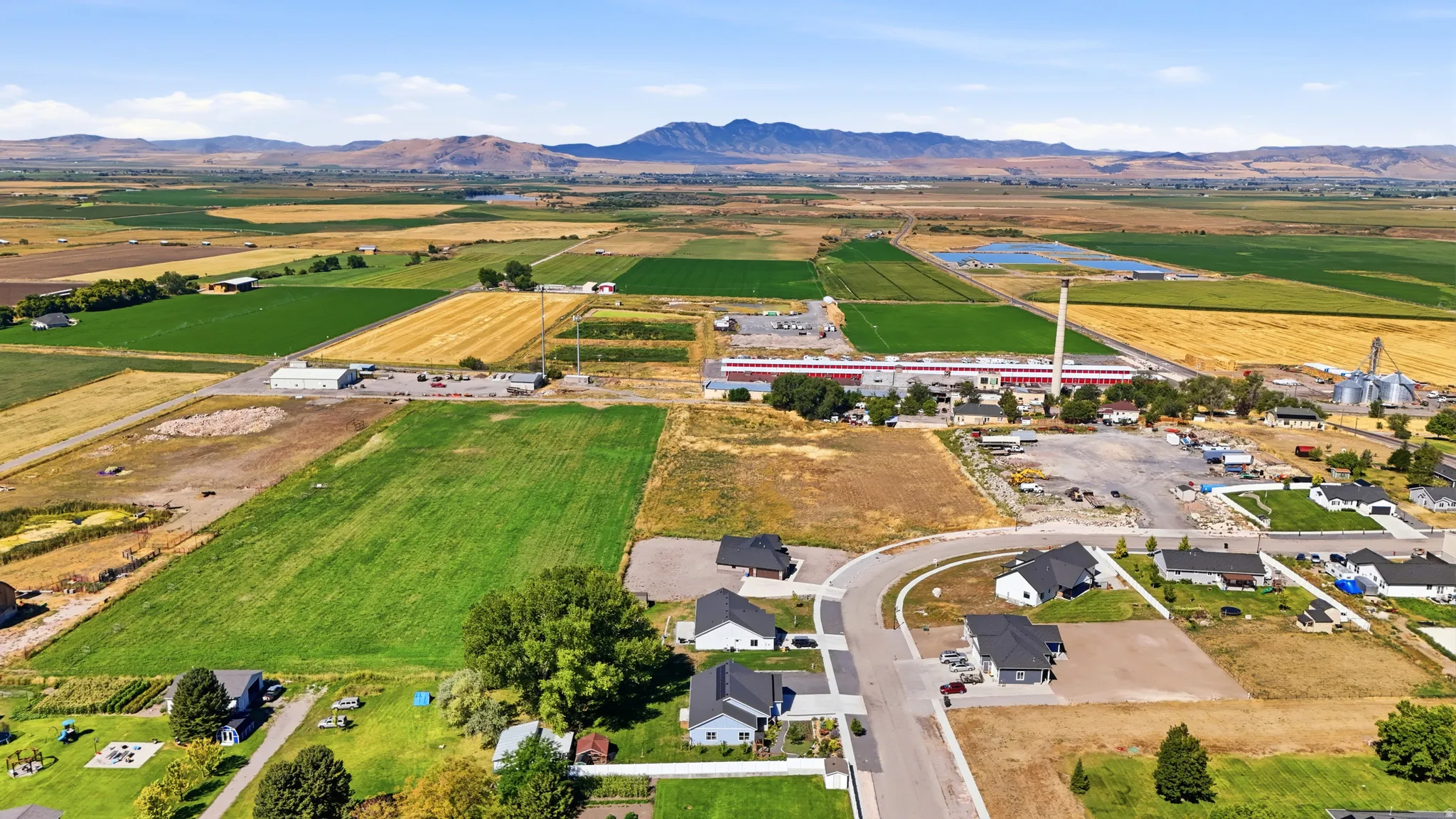 Expansive rural landscape featuring fields, residential areas, and distant mountains