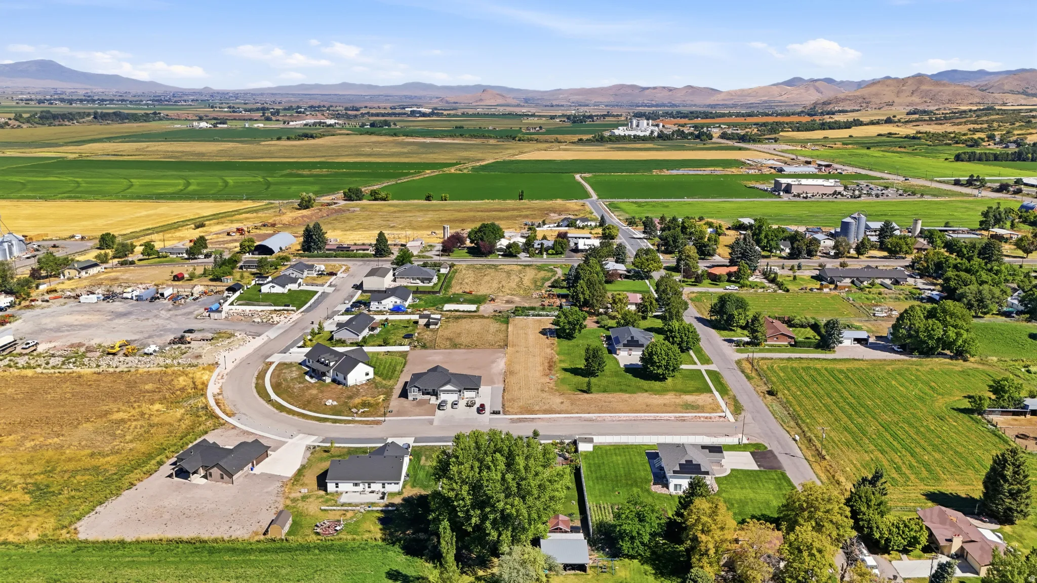 Aerial perspective showcasing residential properties, surrounding farmlands, and distant mountains