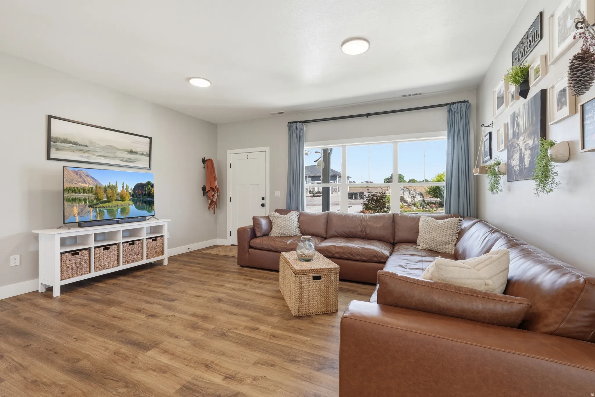 Recessed lighting, wood-finish flooring, white trim, and a window with blue drapes
