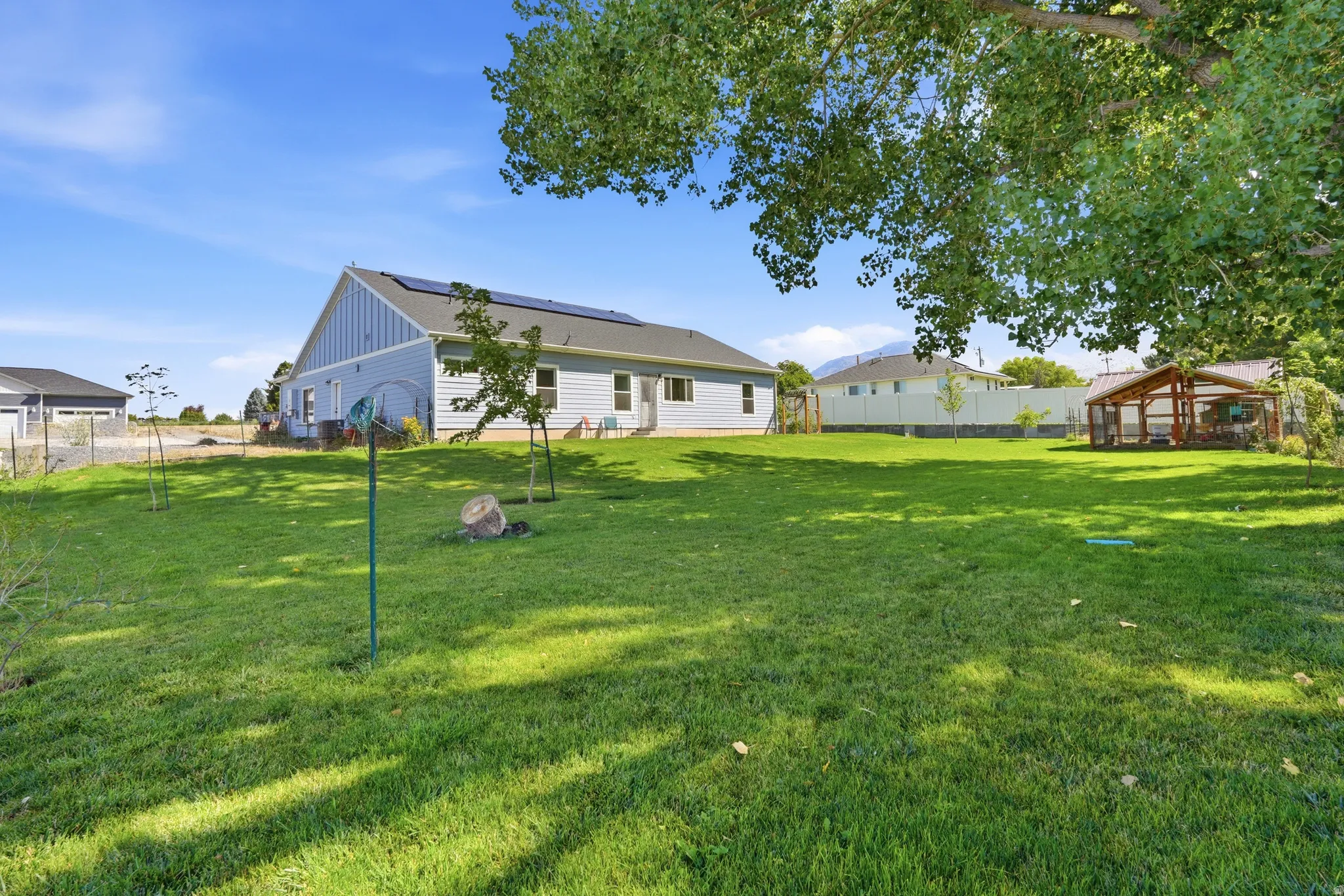Expansive backyard featuring a manicured lawn, established trees, and a detached outbuilding