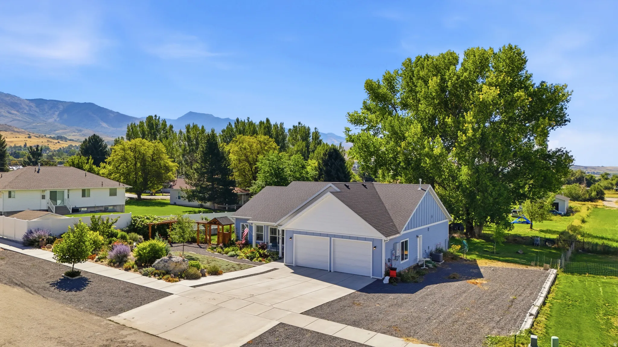 Light blue siding exterior with a dark shingle roof, attached two-car garage, concrete driveway, and front landscaping