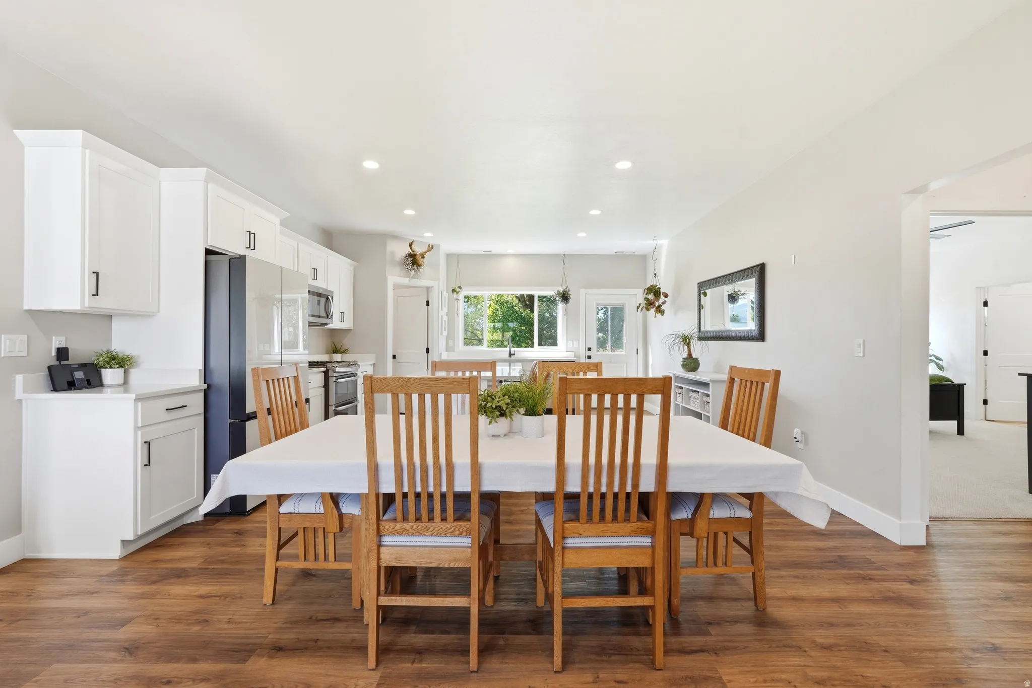 Contemporary kitchen featuring white cabinetry, stainless steel appliances, recessed lighting, and wood-finish flooring
