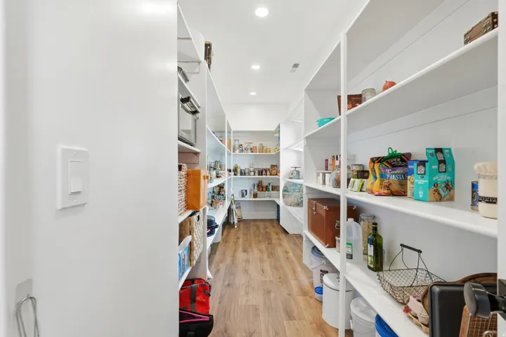 Expansive pantry featuring extensive shelving, recessed lighting, and wood-finish flooring