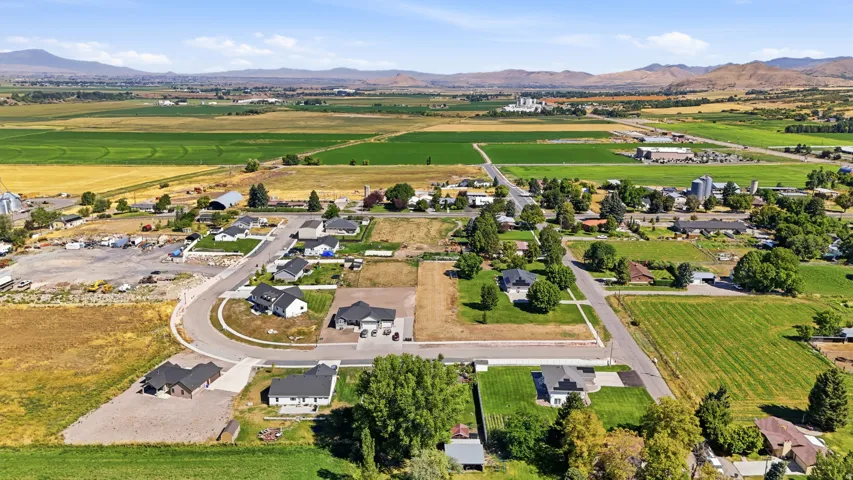 Aerial perspective showcasing residential properties, surrounding farmlands, and distant mountains