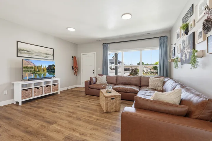 Recessed lighting, wood-finish flooring, white trim, and a window with blue drapes
