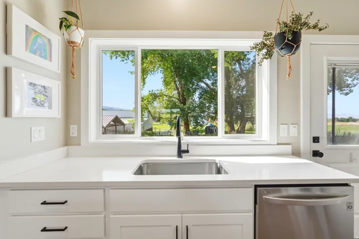 White shaker-style cabinetry with matte black hardware, stainless steel undermount sink, matte black faucet, and white countertops