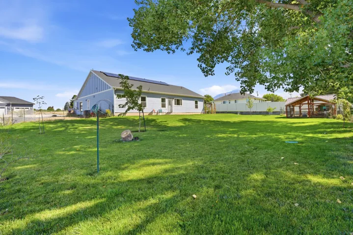 Expansive backyard featuring a manicured lawn, established trees, and a detached outbuilding