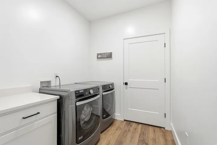 White cabinetry with black hardware, stone-finish countertop, wood-finish flooring, and white interior door
