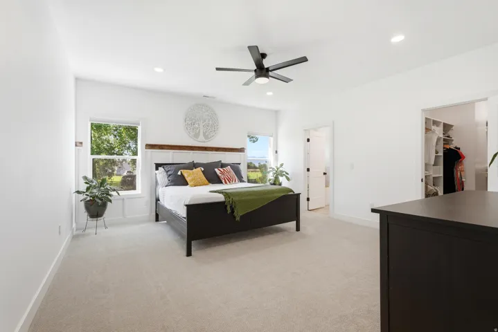 White interior walls, recessed lighting, ceiling fan, carpeted flooring, and built-in closet organization