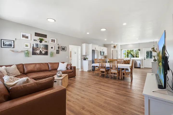 Open-concept living space featuring wood-finish flooring, recessed lighting, white cabinetry, and stainless steel appliances