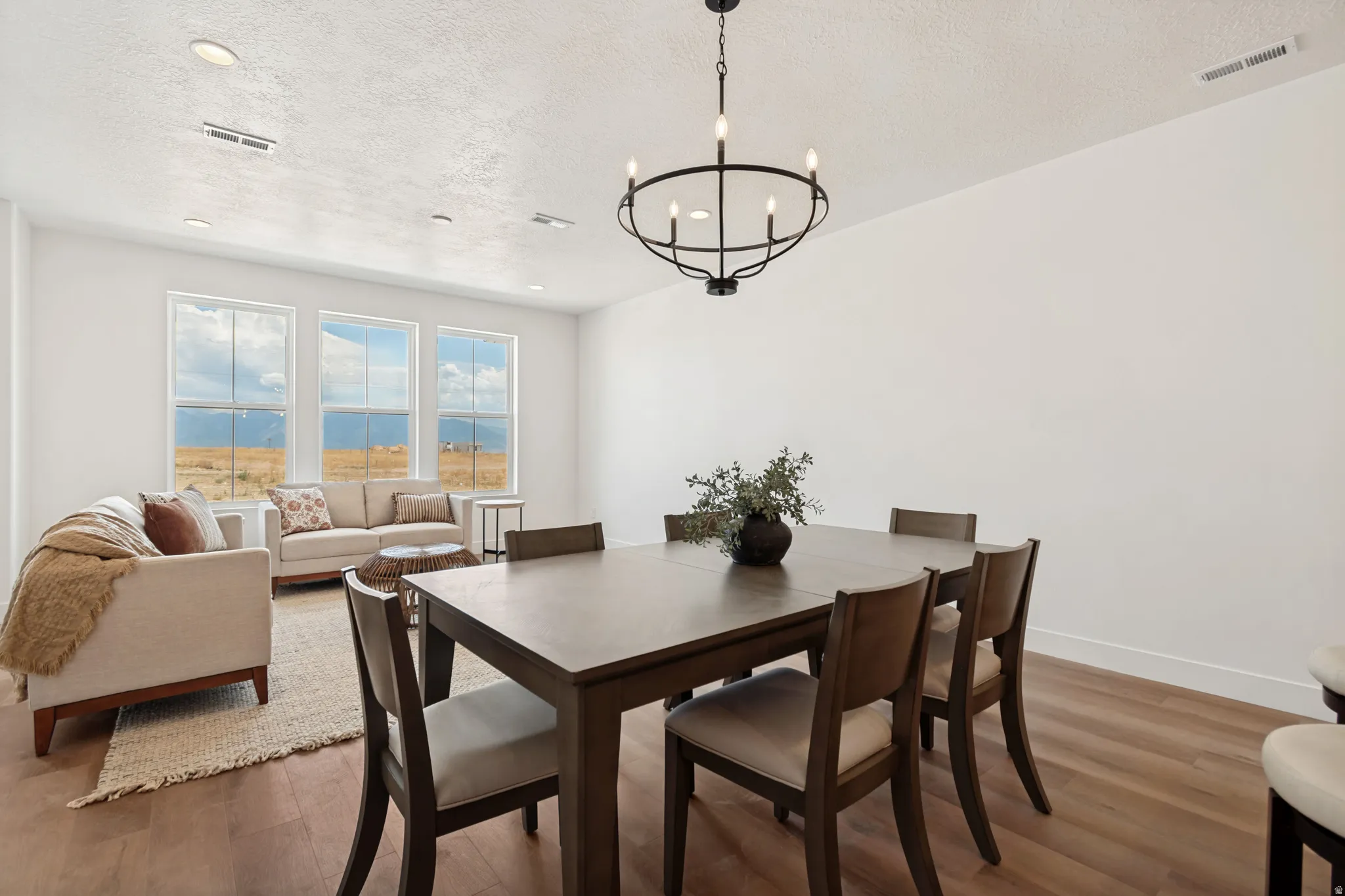 Wood-finish flooring, recessed lighting, and a chandelier with a matte black finish