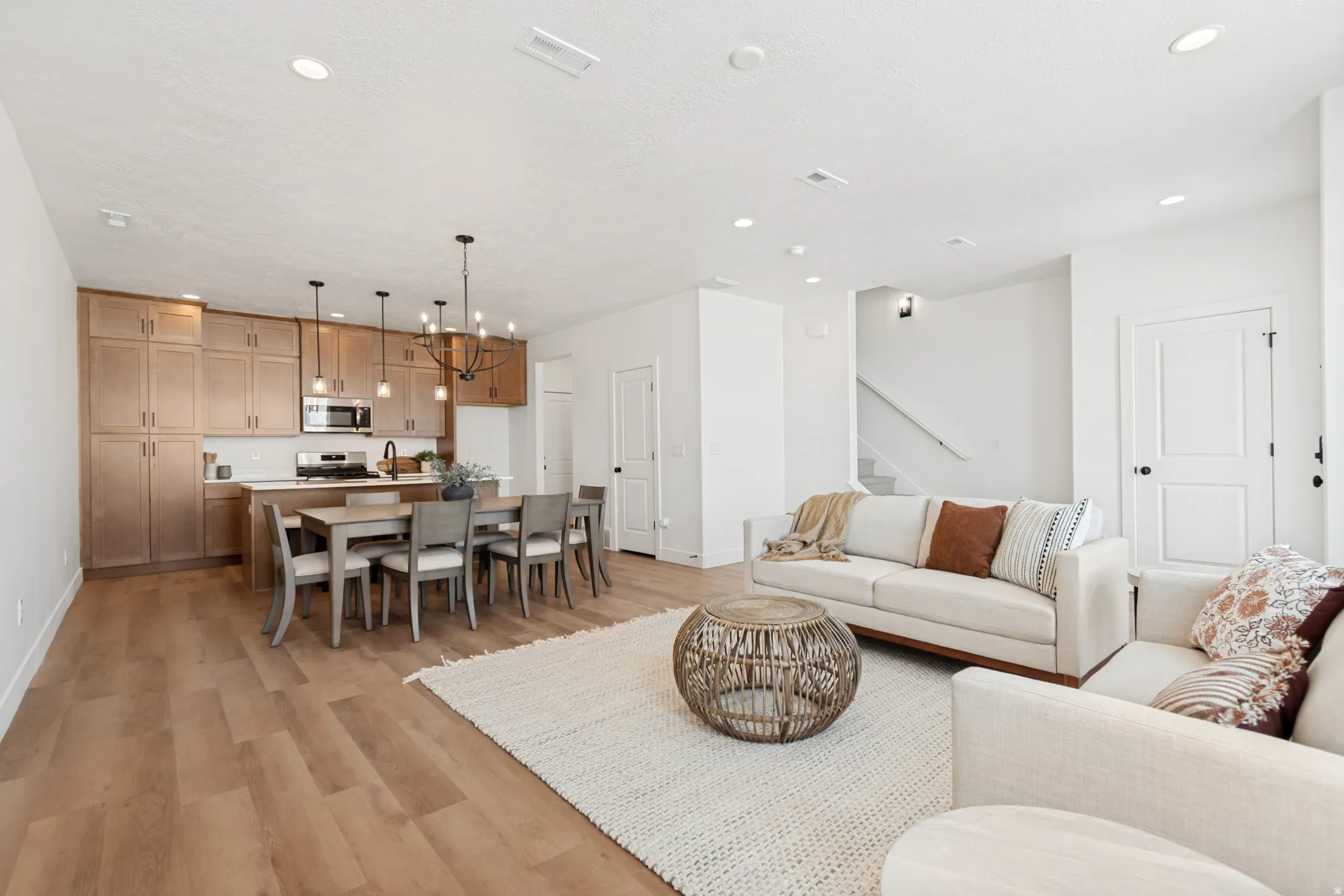 Open-concept living space with wood-finish flooring, a contemporary chandelier, and recessed lighting