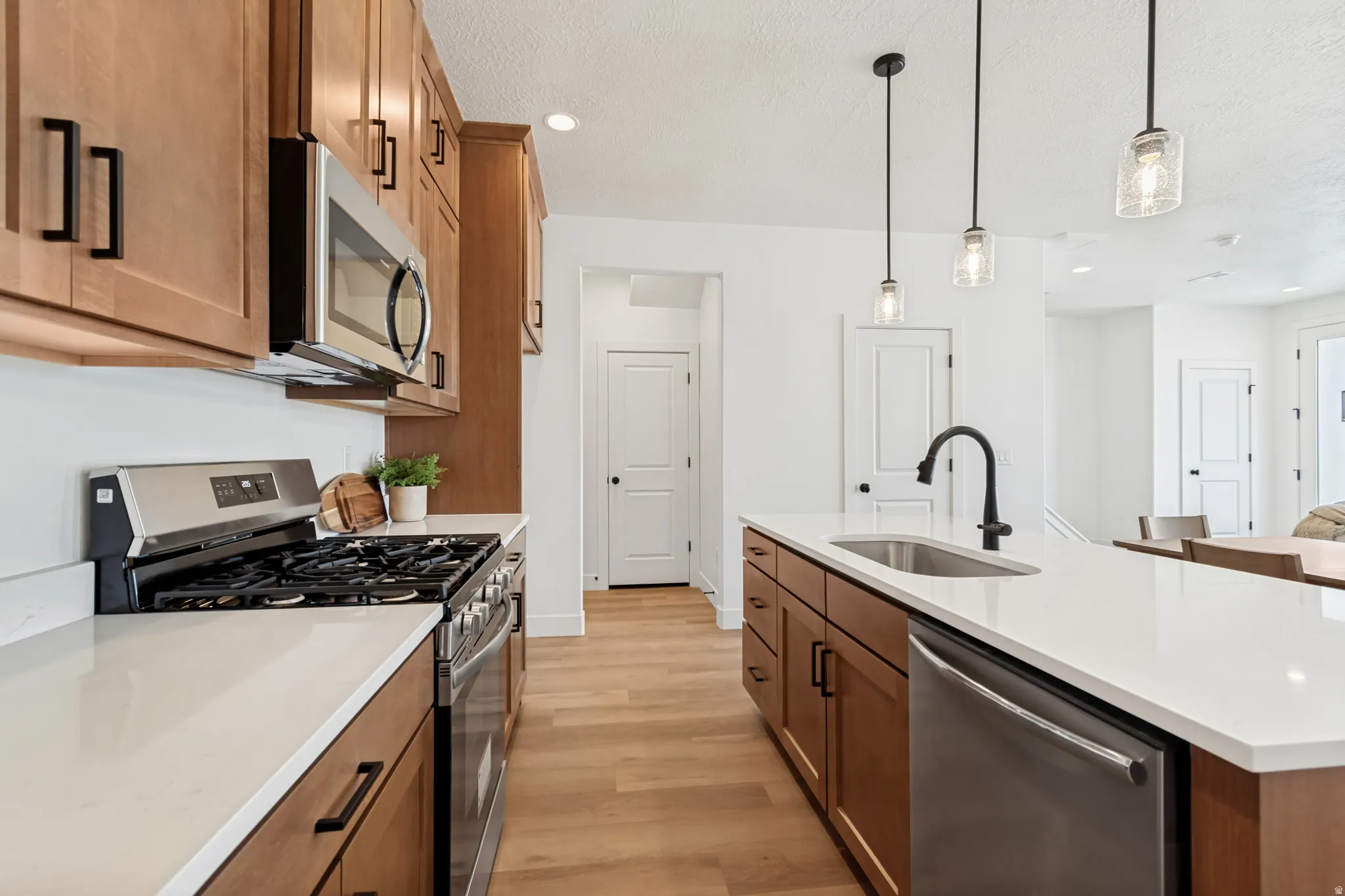 Kitchen featuring extensive wood-finish cabinetry, white countertops, stainless steel appliances, and wood-finish flooring