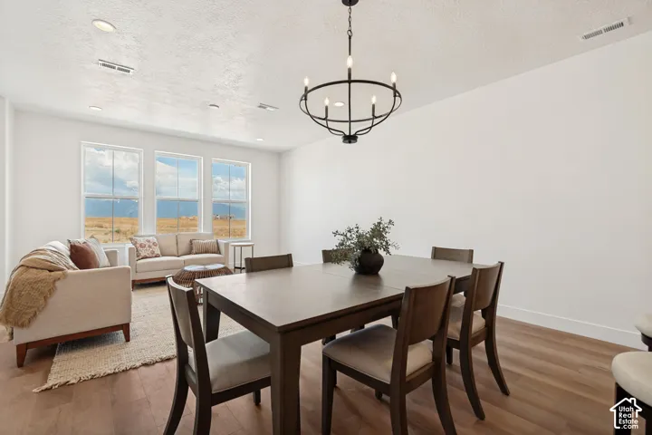 Wood-finish flooring, recessed lighting, and a chandelier with a matte black finish