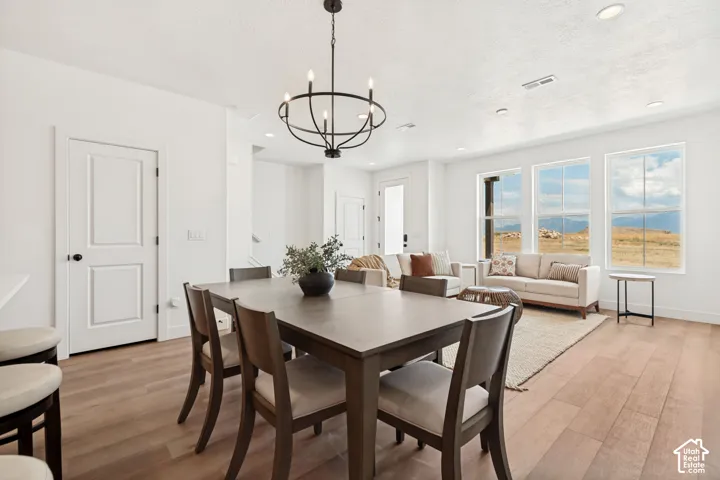 Open-concept living area featuring light wood-finish flooring, recessed lighting, and a contemporary black chandelier