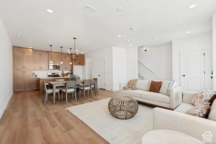 Open-concept living space with wood-finish flooring, a contemporary chandelier, and recessed lighting