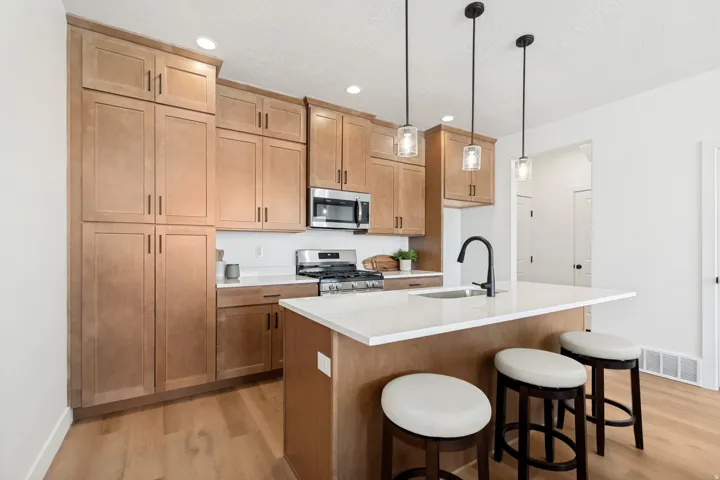 Kitchen featuring extensive wood-finish cabinetry, quartz countertops, stainless steel appliances, and a central island with pendant lighting