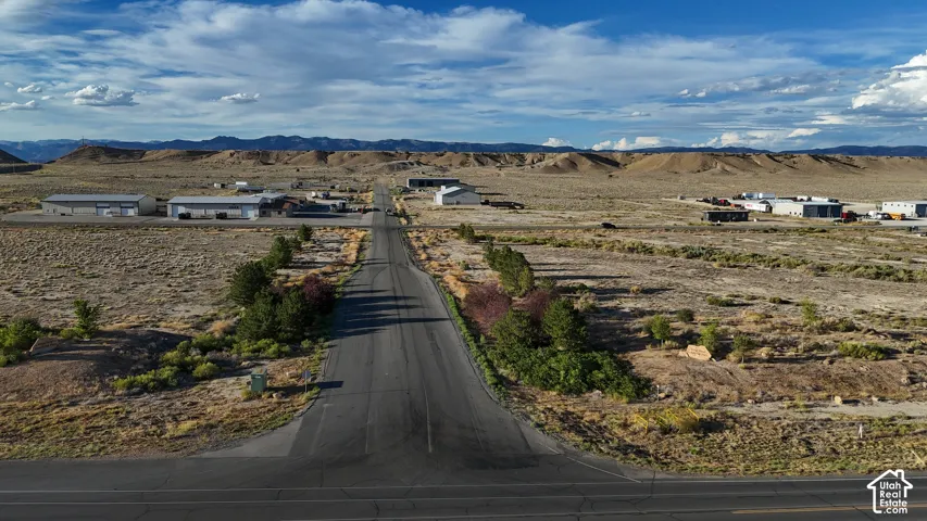 Paved road extending through a broad expanse of arid terrain, surrounded by distant mountains