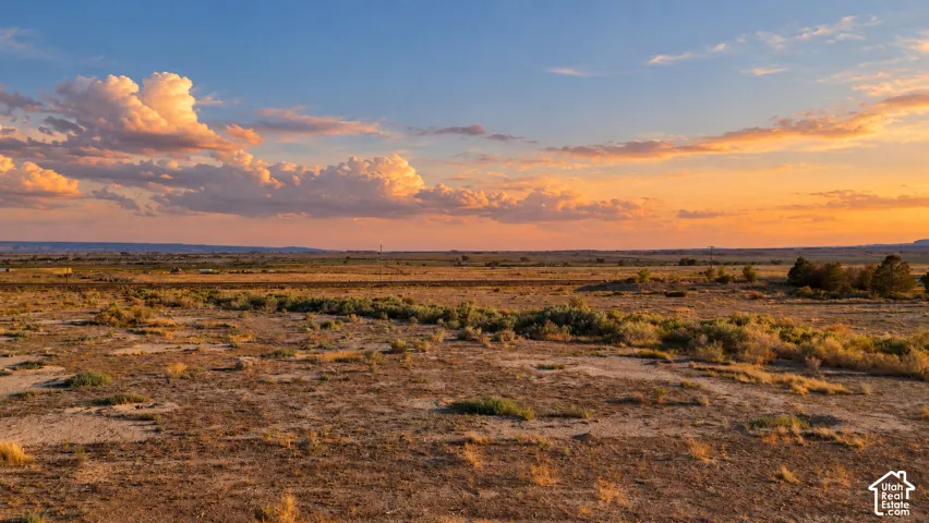 Expansive open terrain with natural vegetation and distant linear features under a broad sky
