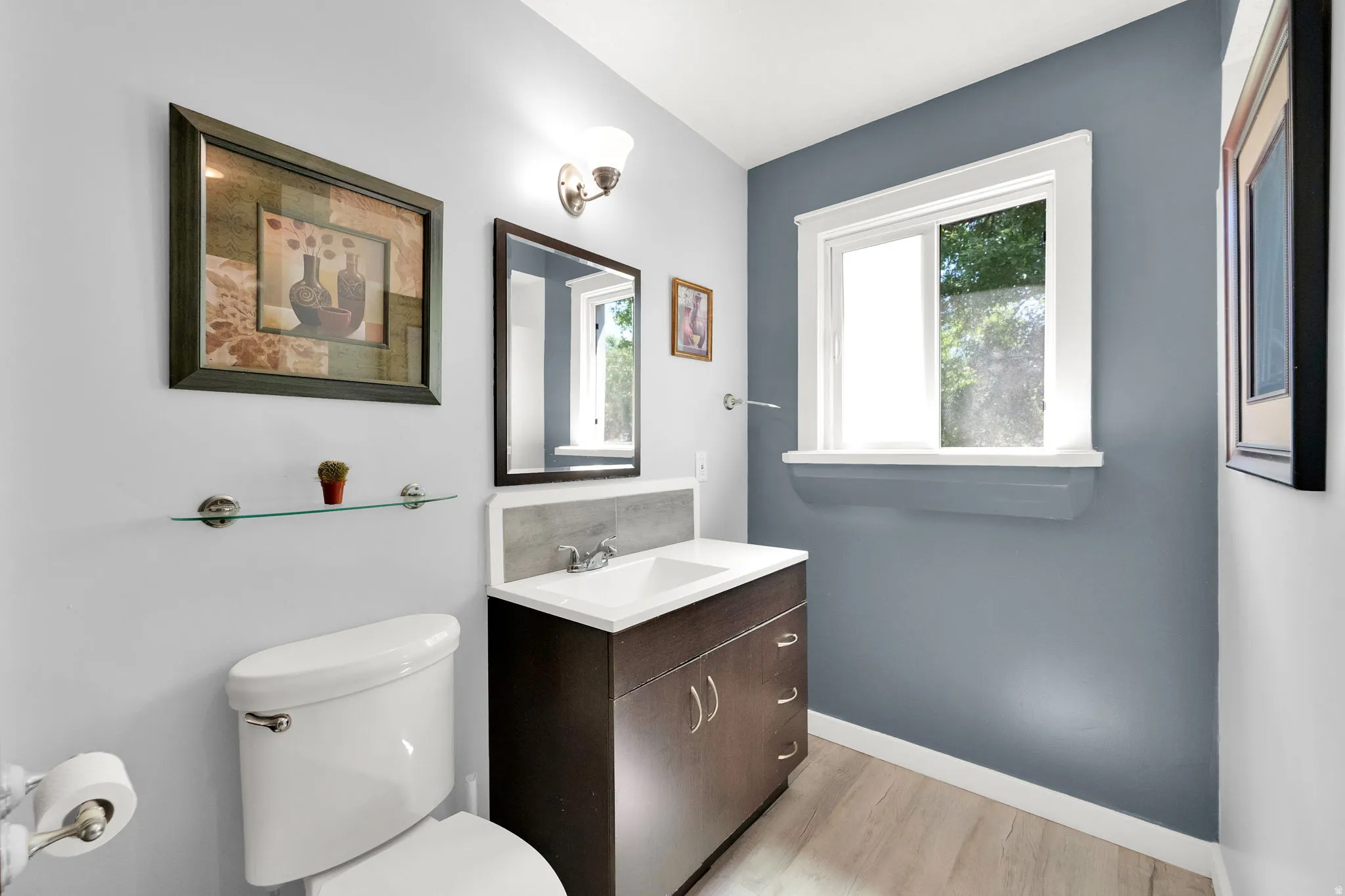 Modern vanity with integrated sink, dark wood-finish cabinetry, and contemporary light fixture