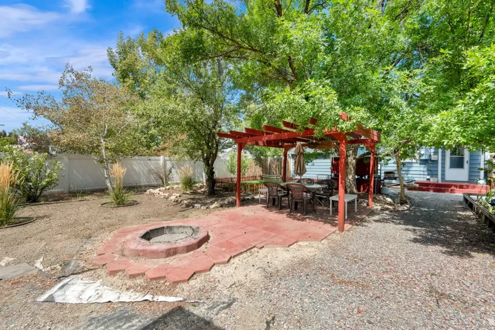 Outdoor living area featuring a red pergola, a paved patio, and a built-in fire pit