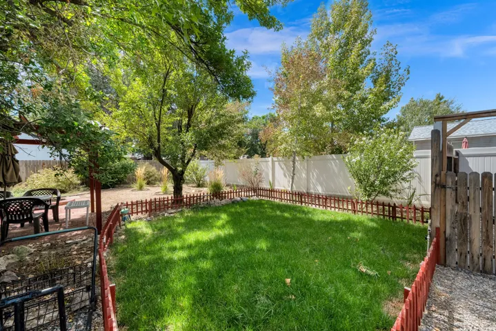 Expansive backyard featuring a manicured lawn, established trees, and a privacy fence