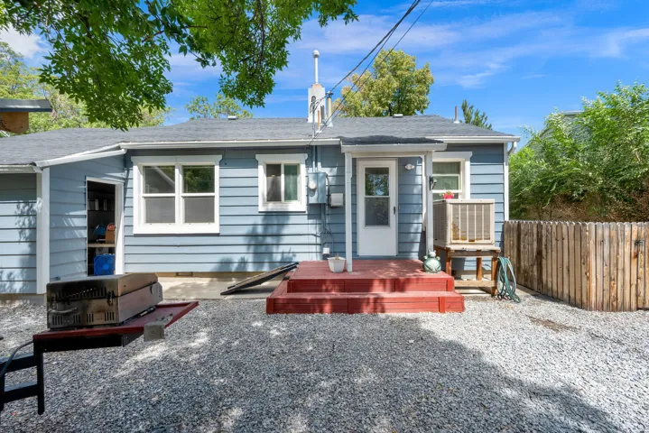 Rear exterior with light blue horizontal siding, white trim, red-painted wood deck, and gravel ground cover