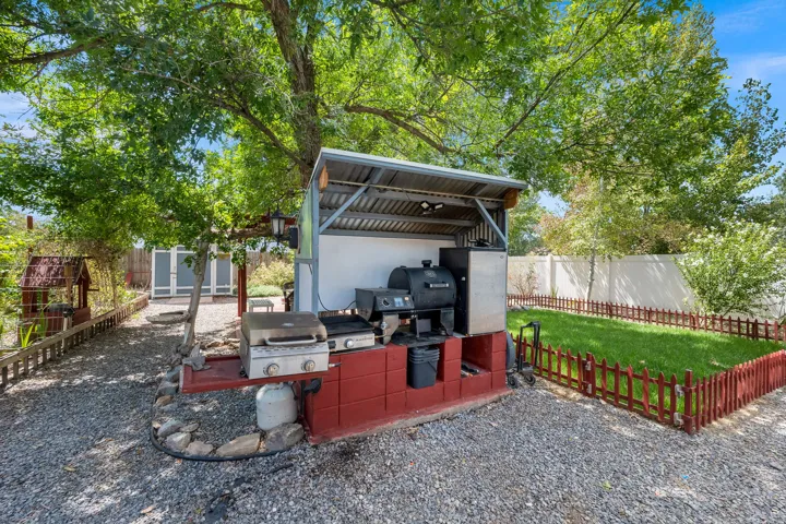 Gravel patio with a built-in outdoor cooking station featuring a corrugated metal roof and red block base