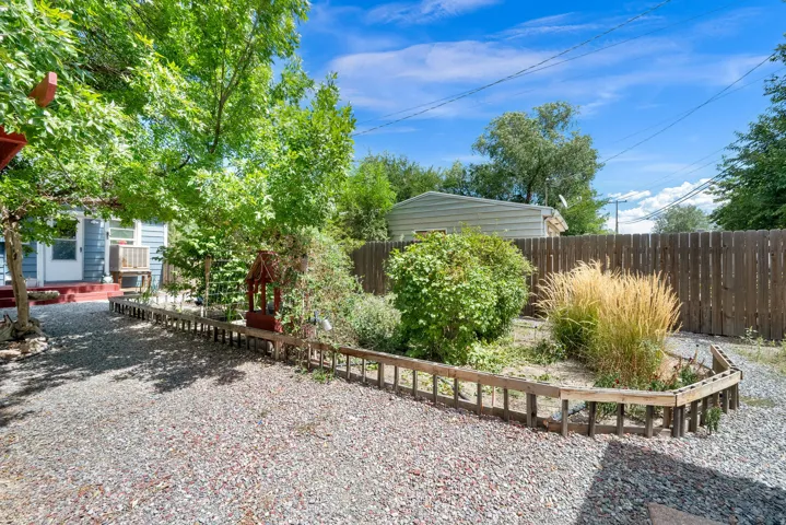 Gravel hardscaping, privacy fencing, established trees, and varied shrubbery create an inviting outdoor space