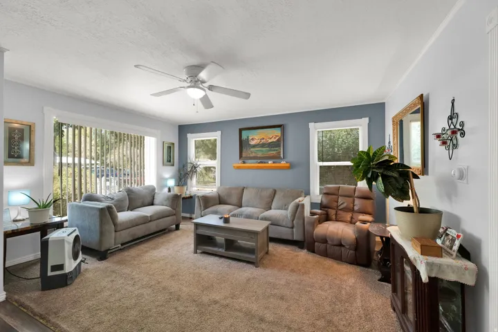 Bright living space featuring a ceiling fan, a large window with vertical blinds, and a secondary window