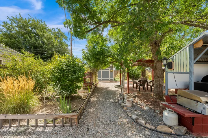 Landscaped backyard with gravel pathways, established trees, and a covered patio area
