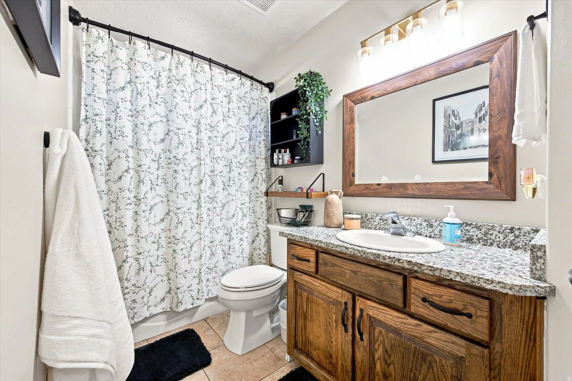 Wood-finish vanity with a granite-style countertop, oval undermount sink, and a framed mirror