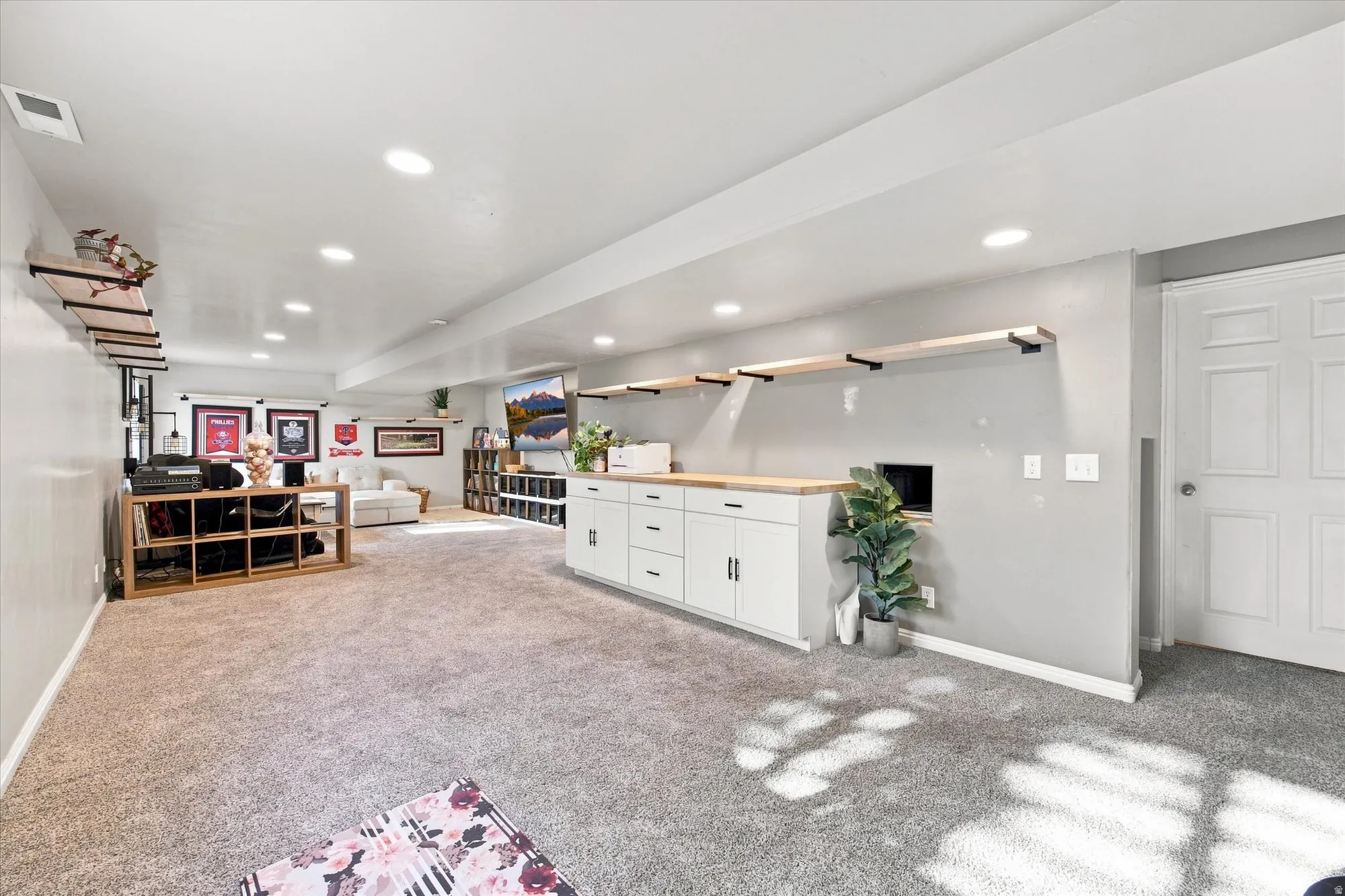 Recessed ceiling lighting, wood-finish shelving with black metal supports, built-in lower cabinetry, wood-finish countertop, and wall-to-wall carpeting