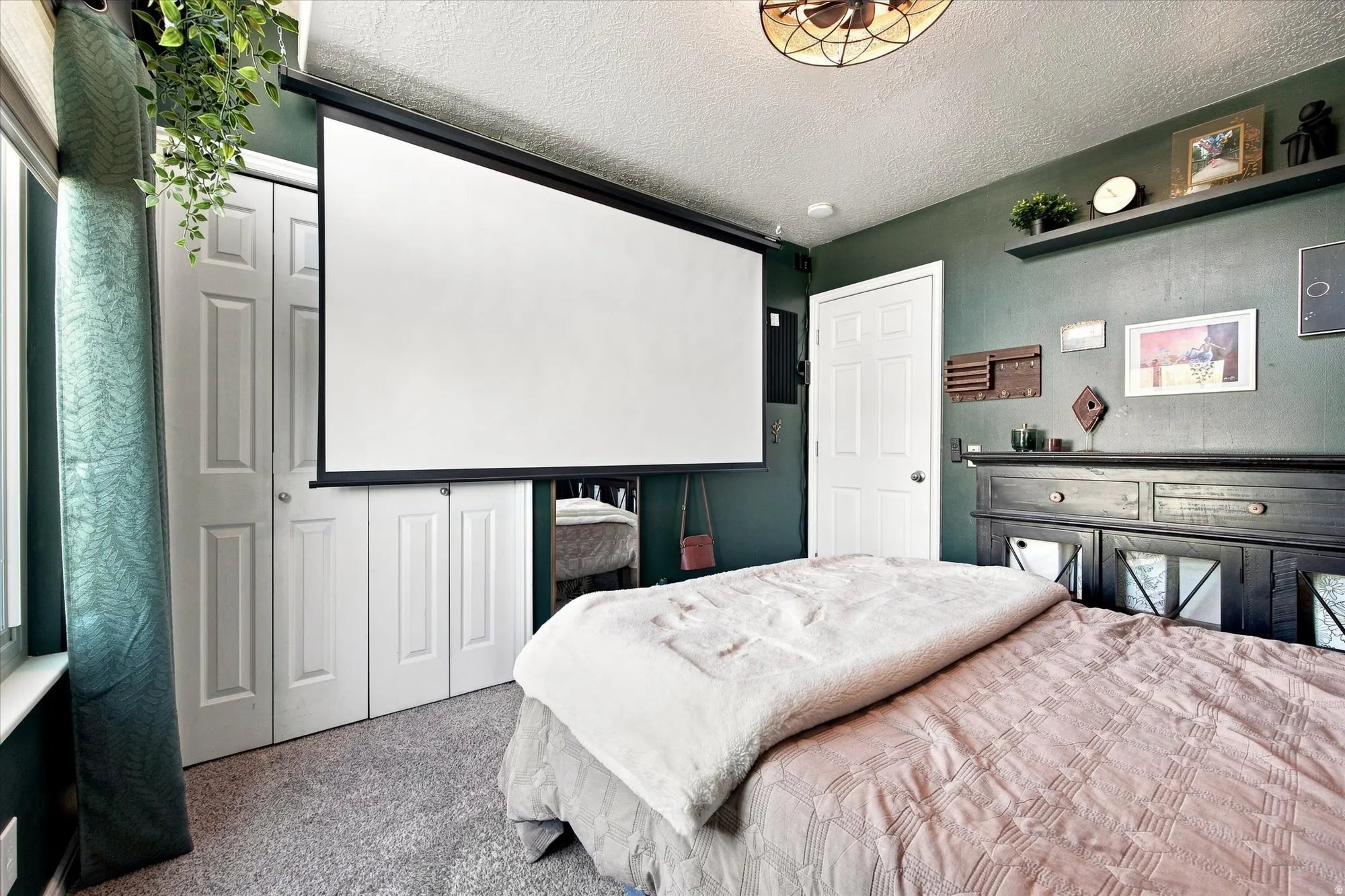 Retractable projection screen, ceiling-mounted fan, floating wall shelf, paneled interior door, and bi-fold closet doors