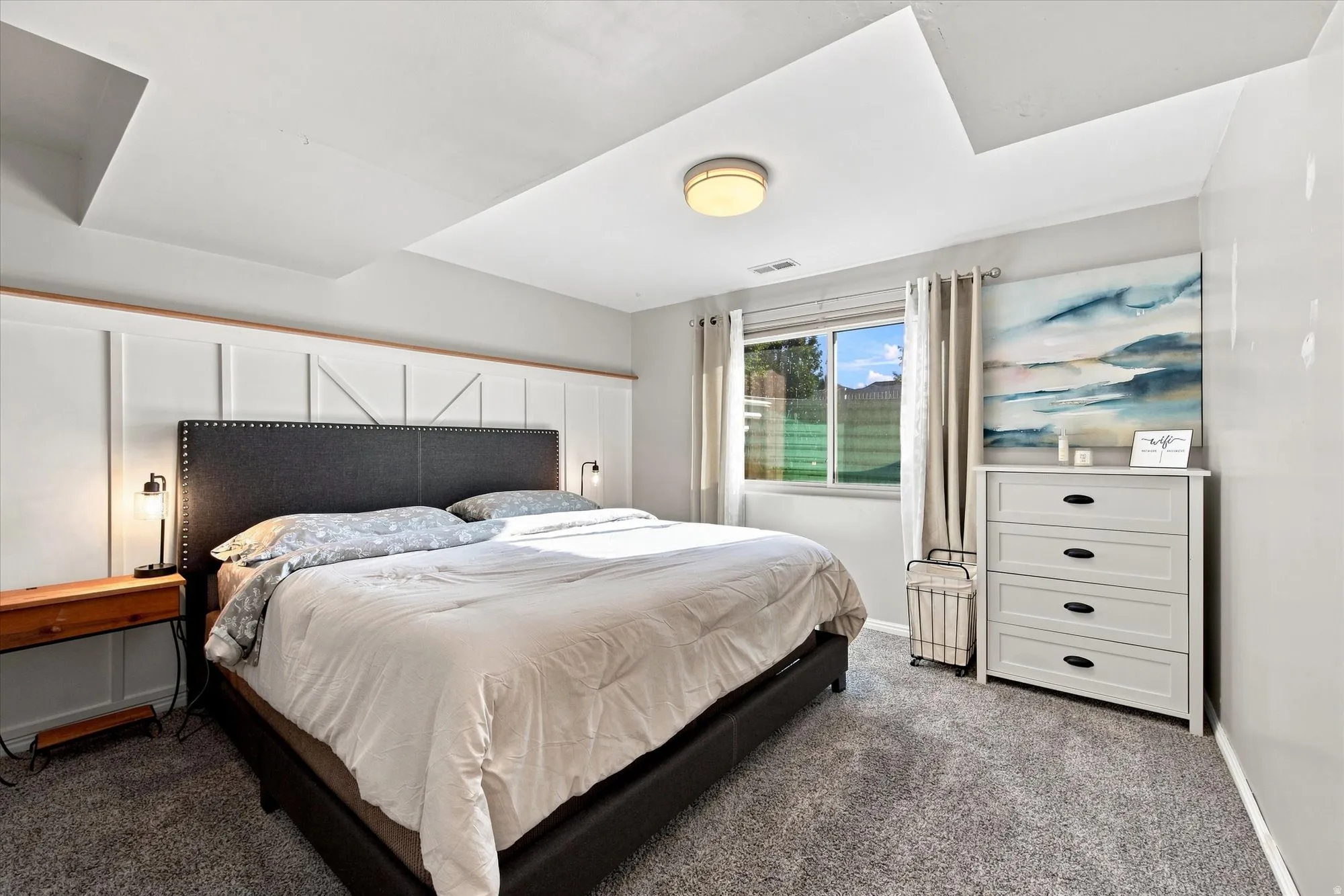 Recessed ceiling details, carpeted flooring, and a large window with roller shades