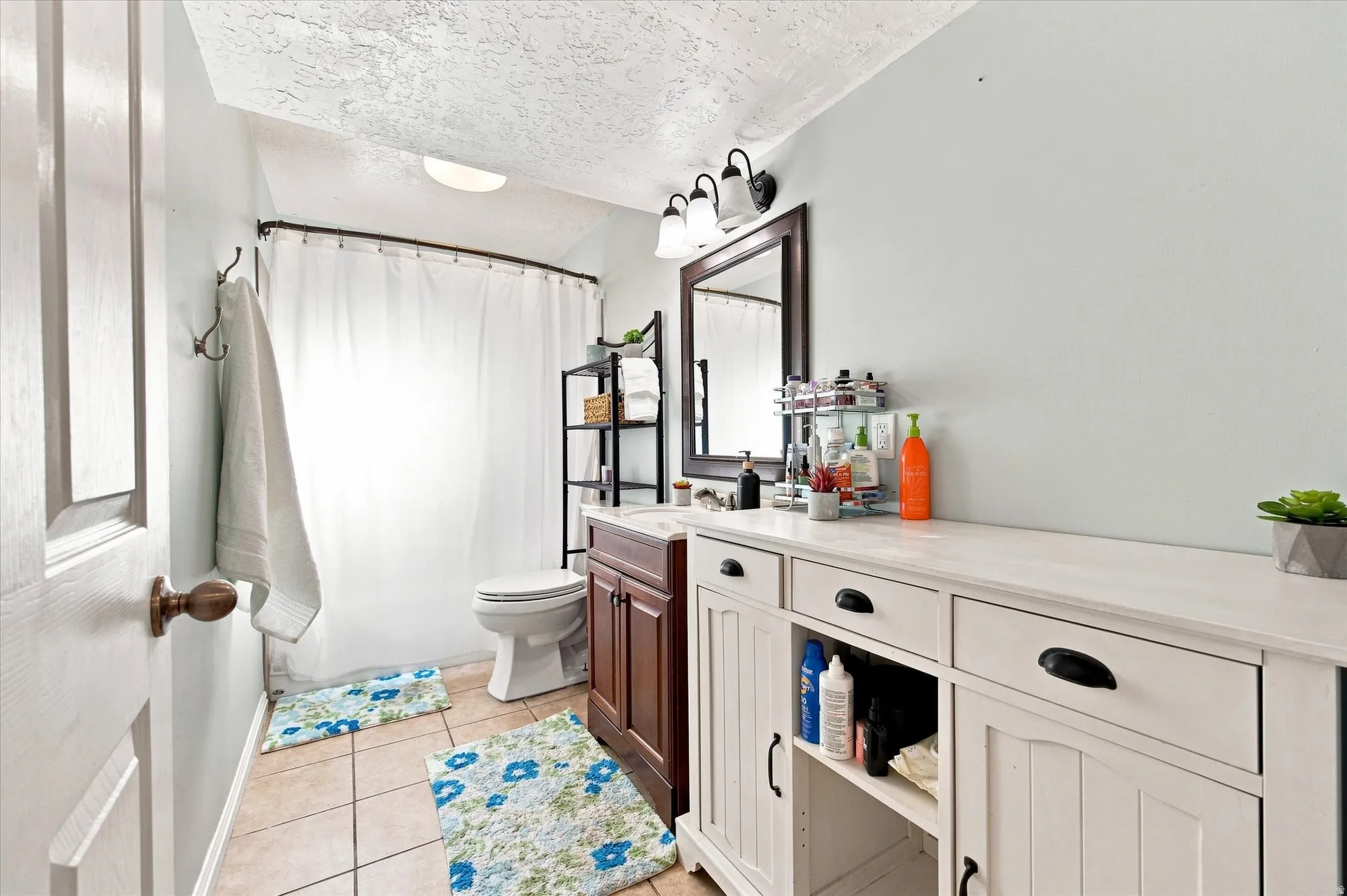 Wood-finish vanity with countertop, framed wall mirror, and tiled flooring