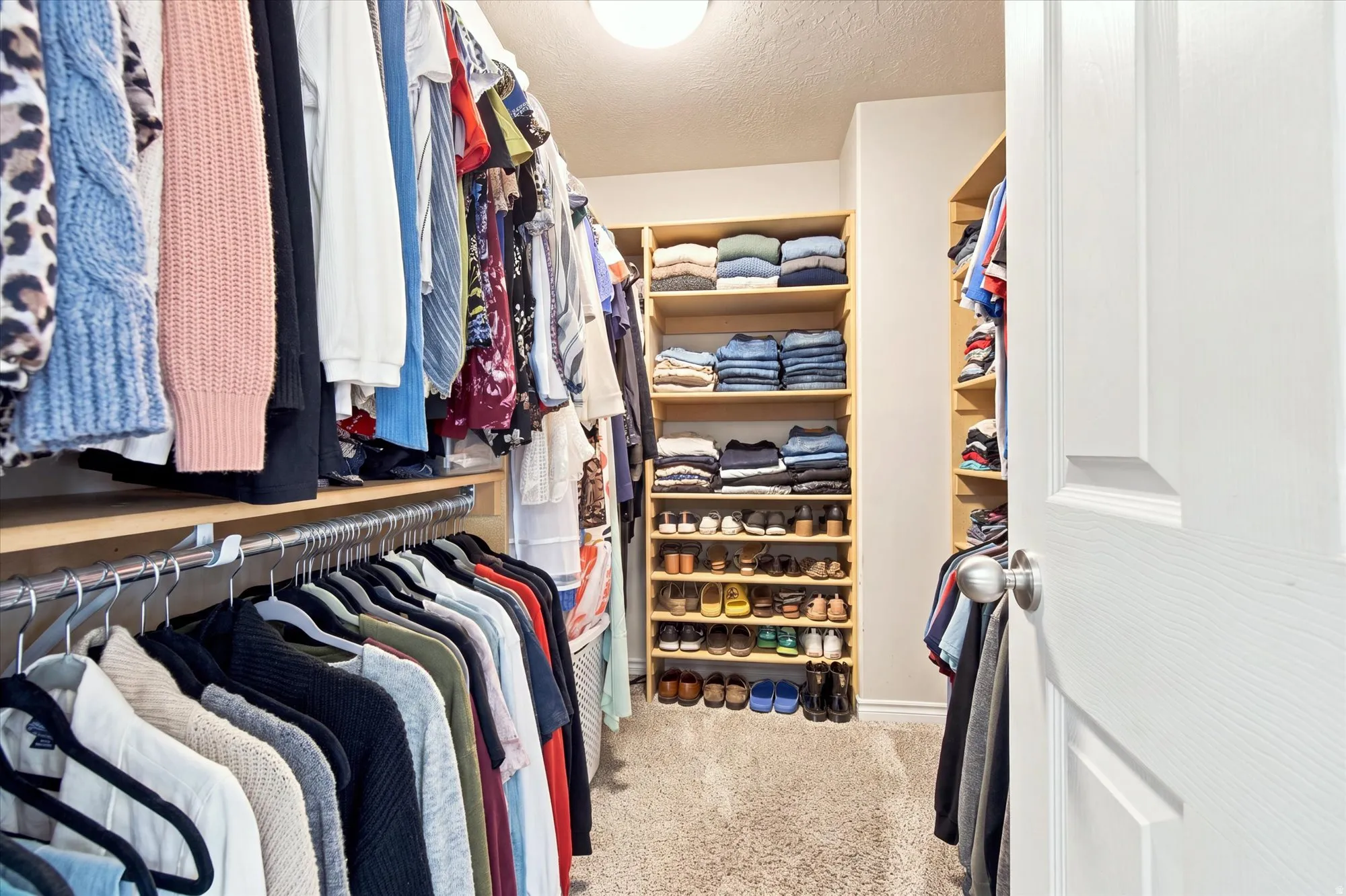 Walk-in closet featuring carpet flooring, built-in shelving, and multiple hanging rods