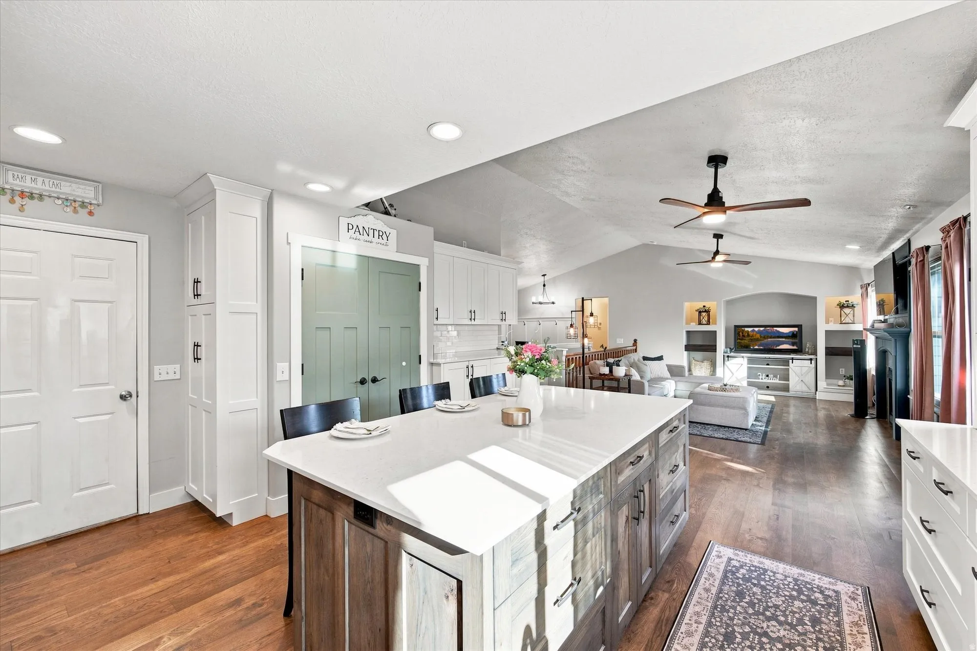 Kitchen featuring a large island with a light-toned countertop, white cabinetry, a pantry door, recessed lighting, and wood-finish flooring