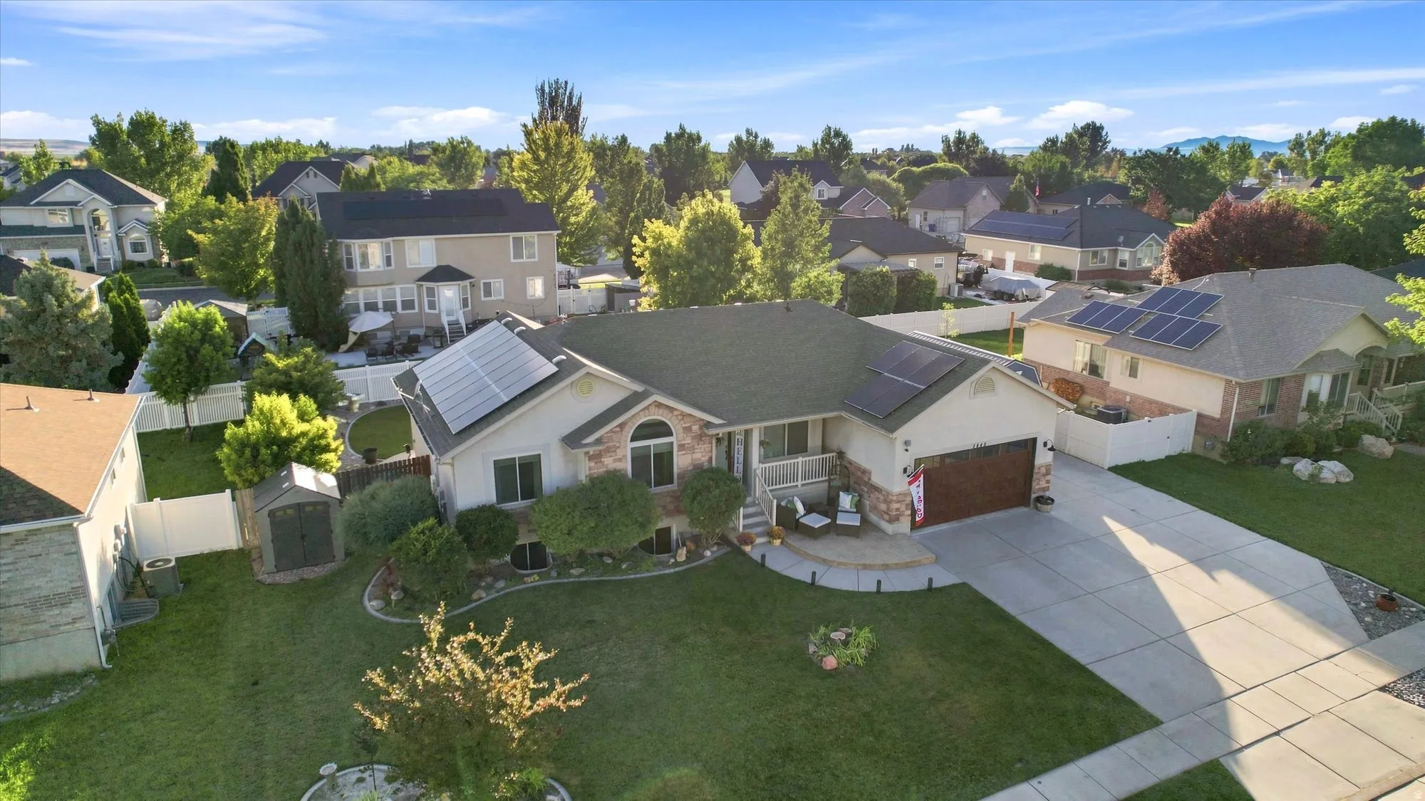 Single-story residence featuring a two-car garage, solar panels, and a concrete driveway