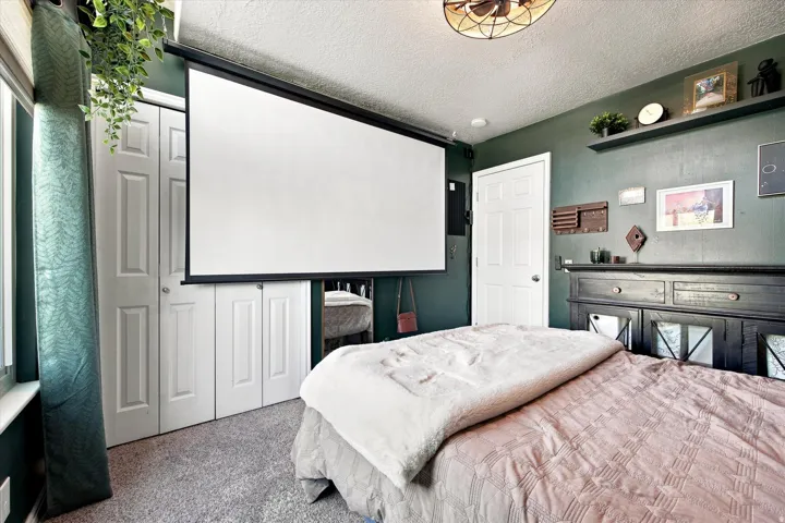 Retractable projection screen, ceiling-mounted fan, floating wall shelf, paneled interior door, and bi-fold closet doors