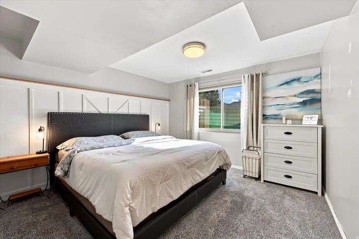 Recessed ceiling details, carpeted flooring, and a large window with roller shades