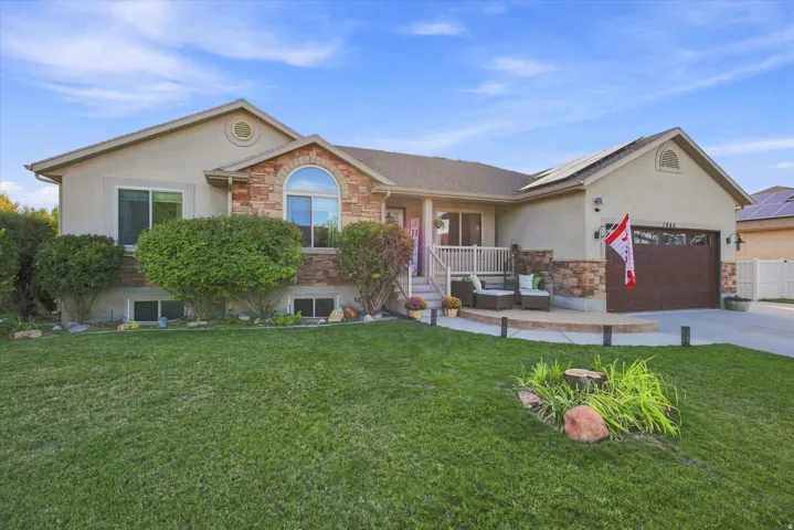 Stucco and stone exterior with an arched window, a covered porch, and an attached garage with a wood-finish door